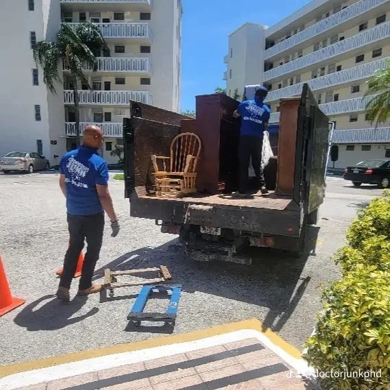 Movers loading furniture into a truck outside an apartment building on a sunny day.