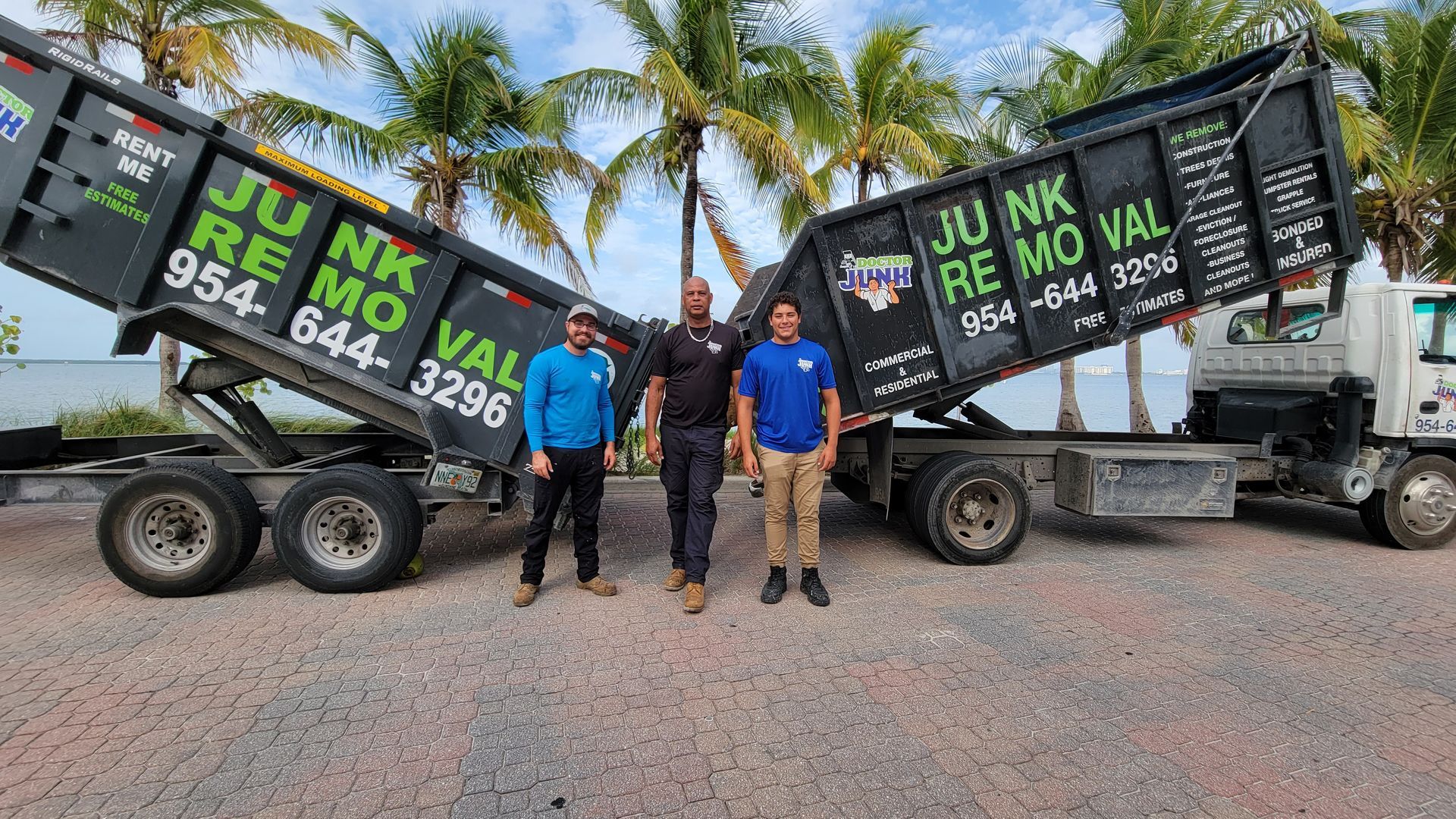 Three men stand in front of a Junk Removal truck in front of palm trees.