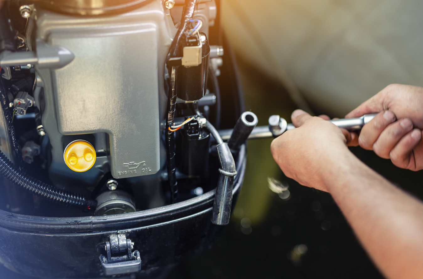 A man is working on a boat engine with a wrench.