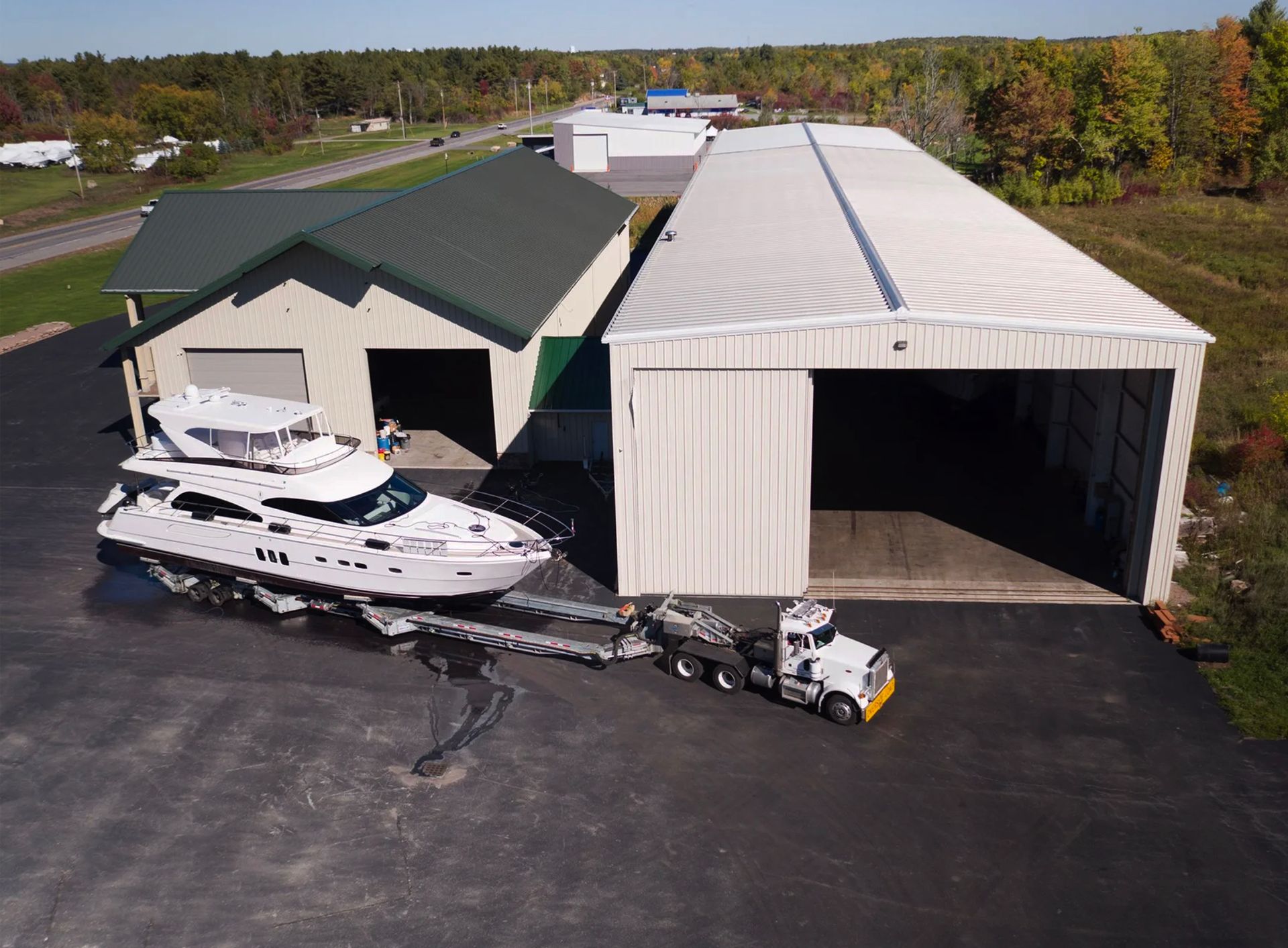 An aerial view of a boat being towed by a truck in front of a building.