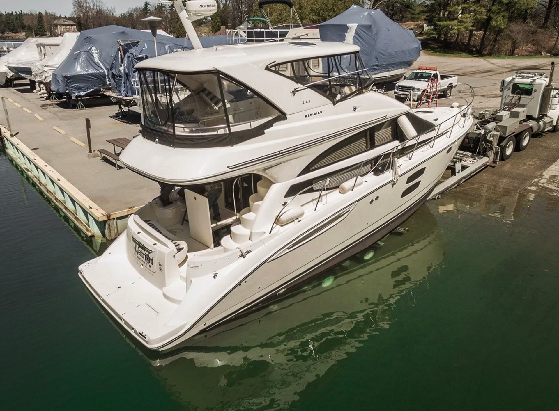 A large white boat is being towed by a tow truck.