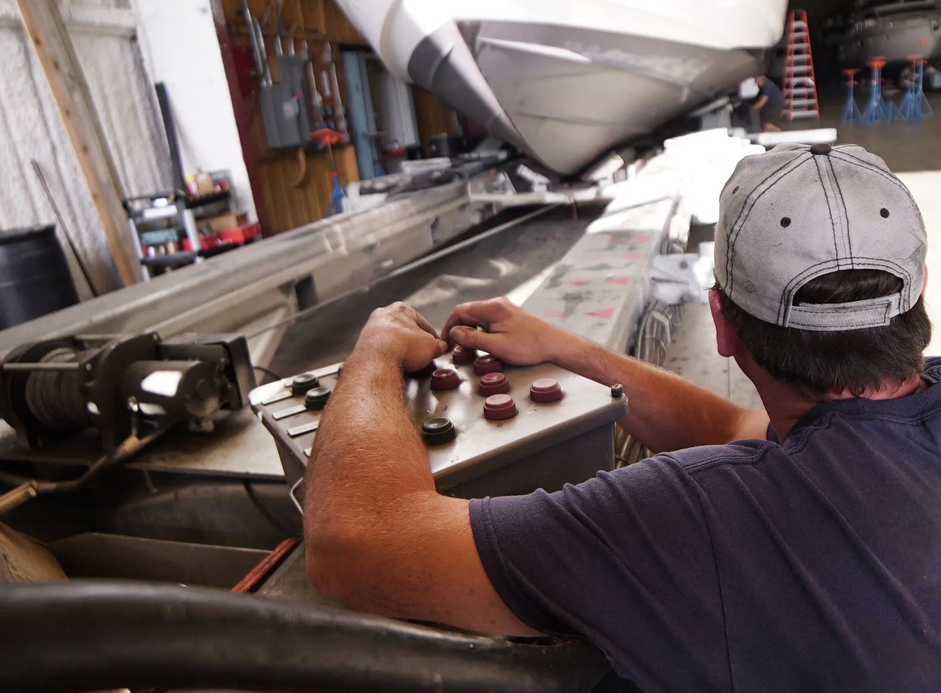 A man wearing a baseball cap is working on a machine.
