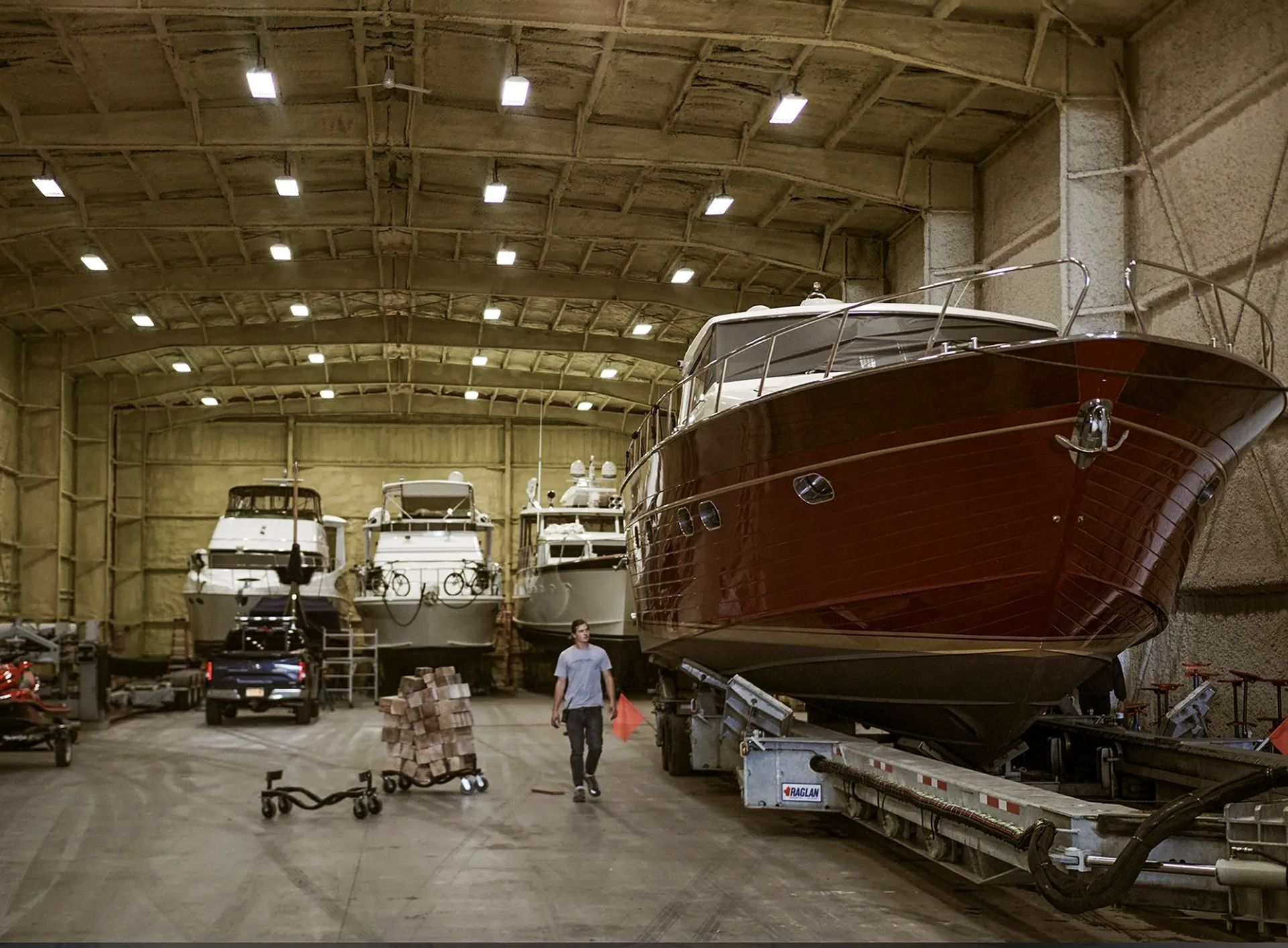A man is pushing a boat on a trailer in a warehouse.