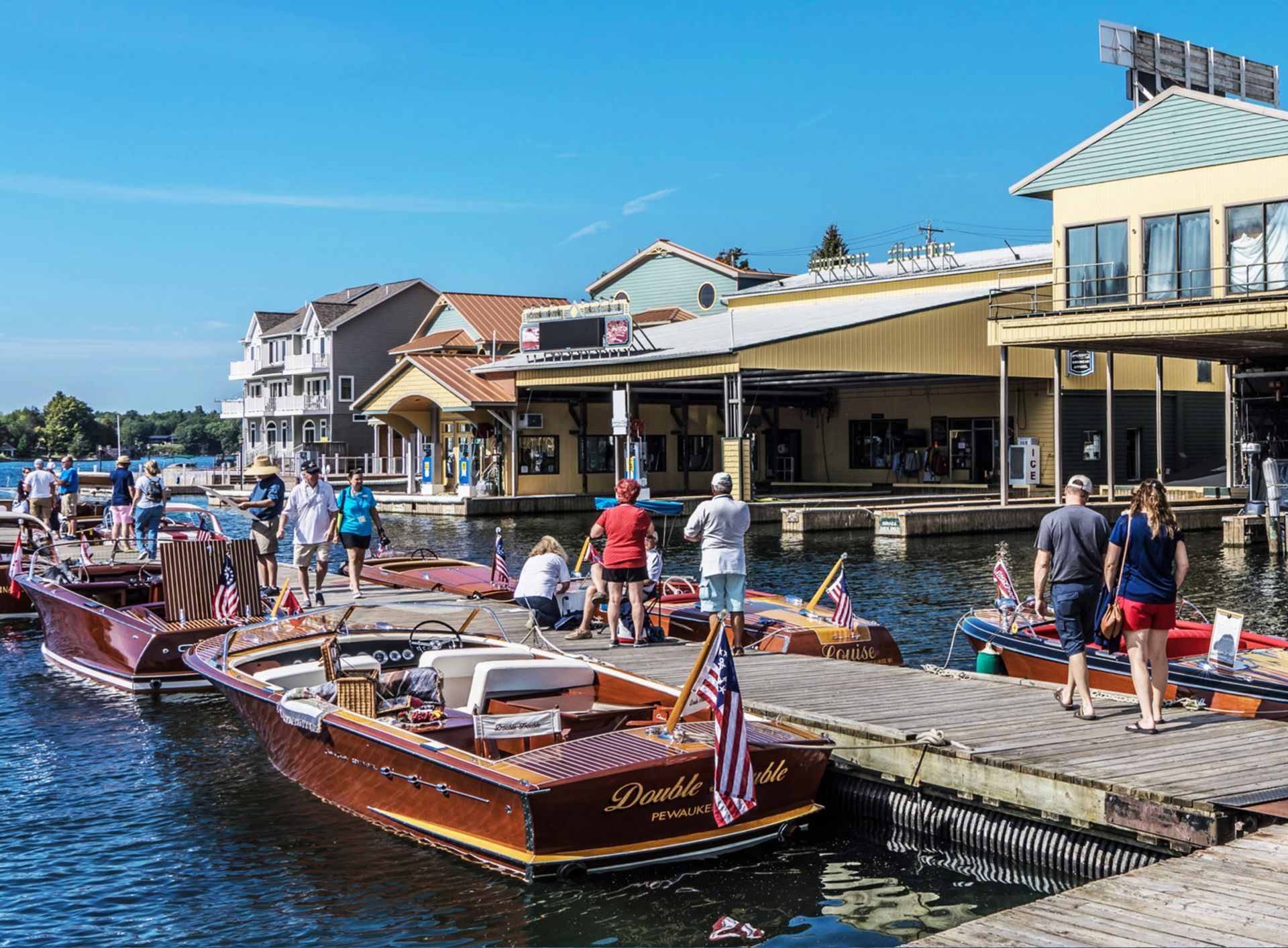 A group of people are standing on a dock next to boats.