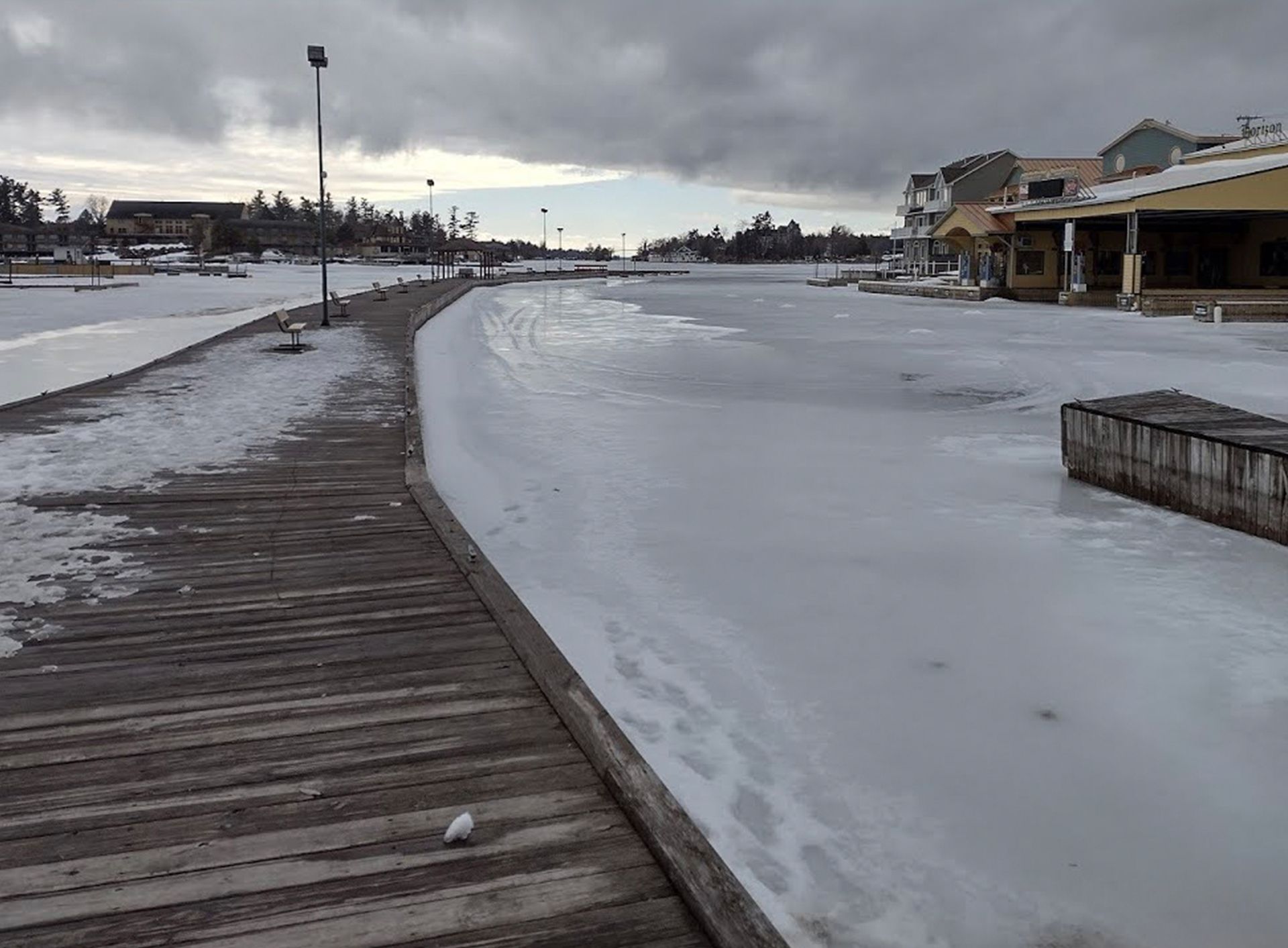 A snowy dock with a few buildings in the background