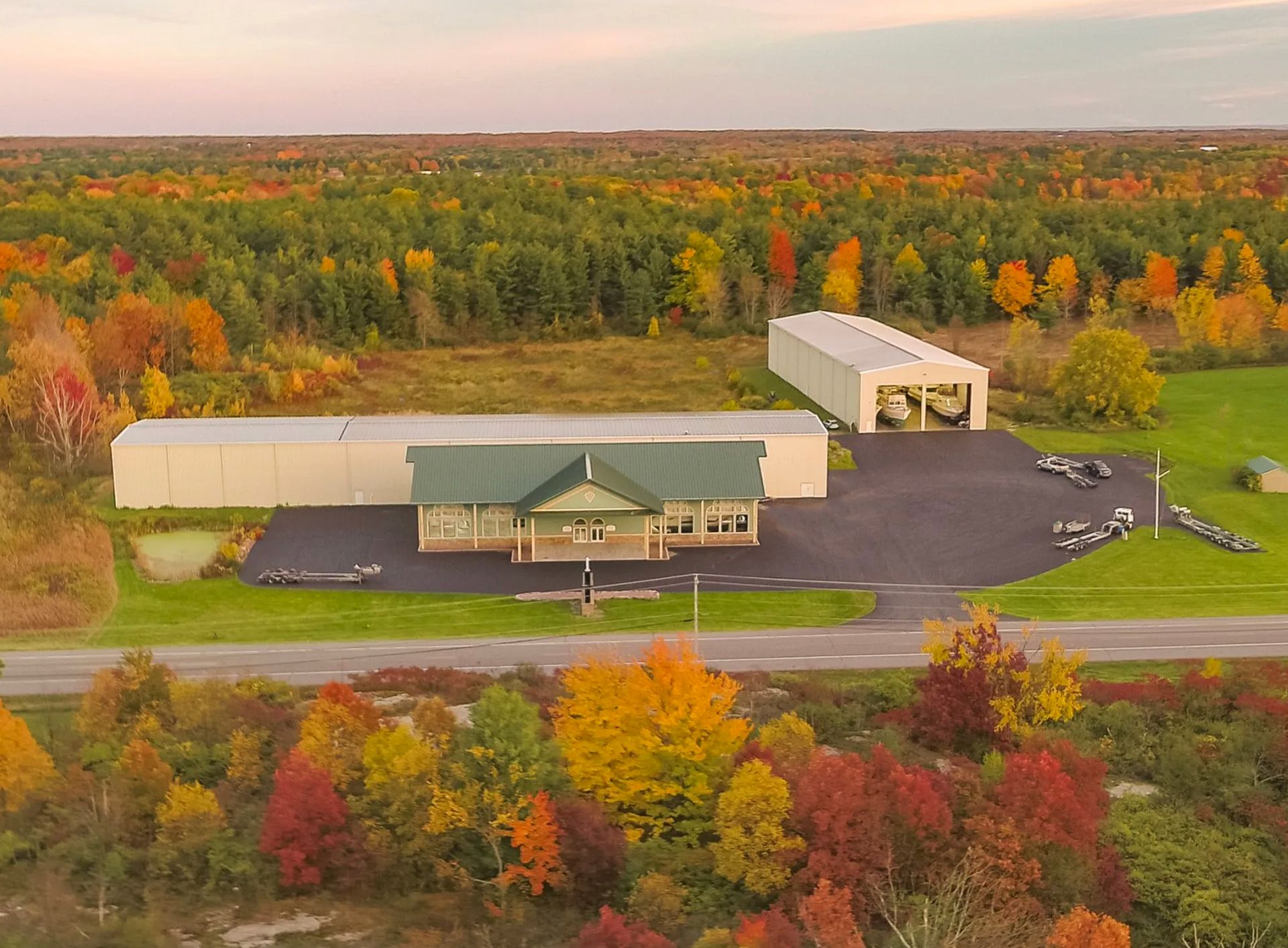 An aerial view of a house and a hangar in the middle of a forest.