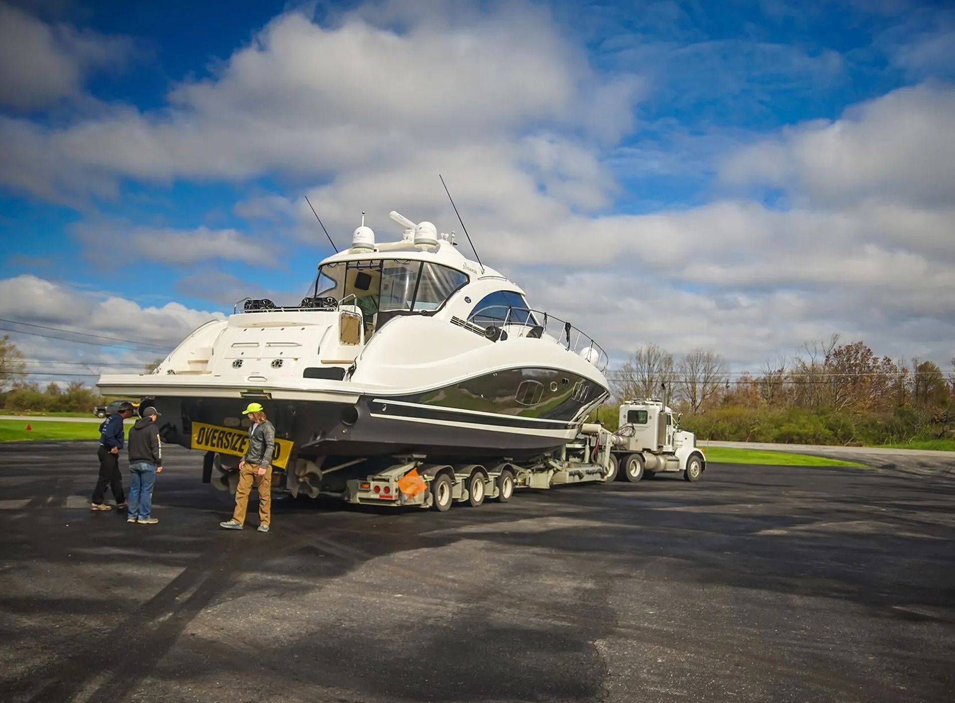 A large yacht is being towed by a semi truck.