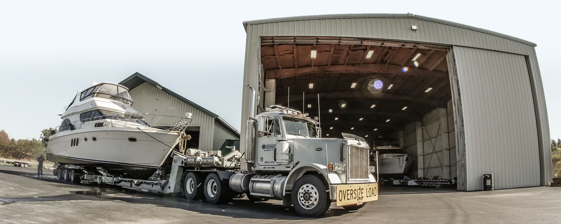 A semi truck is carrying a boat into a building.