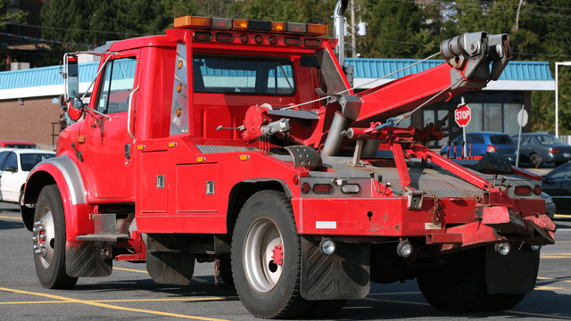 Red tow truck lifting a vehicle onto a flatbed in milford mill, md