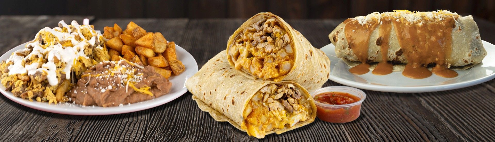 Plates of Mexican food, including burritos, beans, potatoes, and salsa.