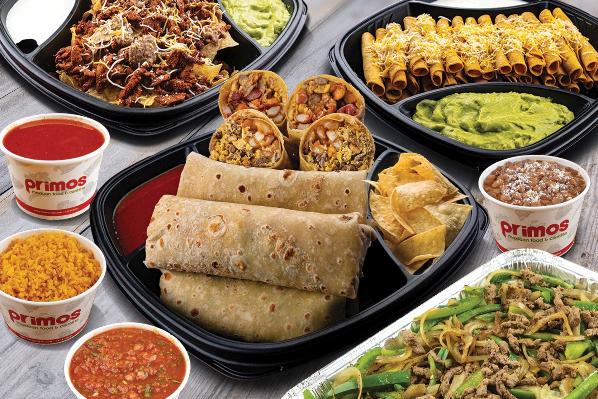 Fries topped with meat, cheese sauce, and red chips on paper with a logo. A hand holds a fork.