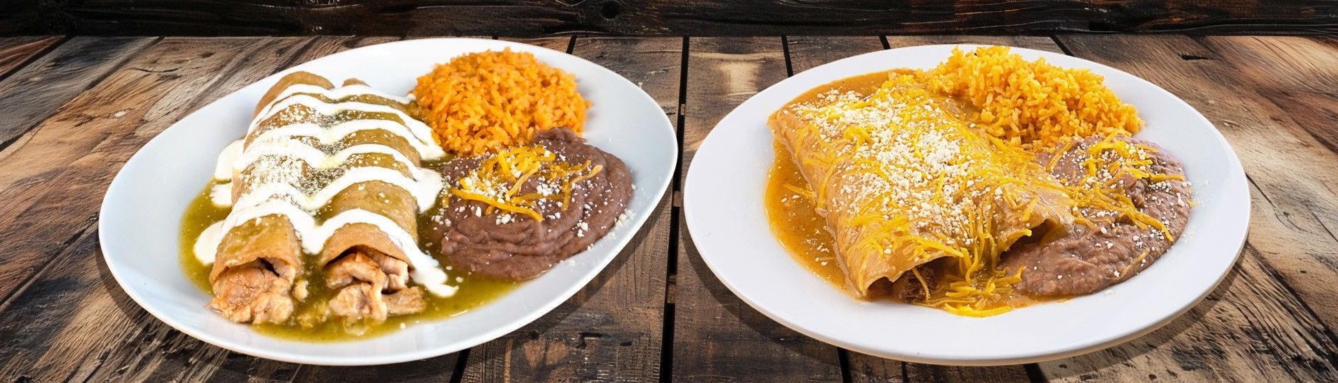 Two plates of enchiladas with rice and beans on a wooden table. One plate with white sauce, the other with yellow sauce.