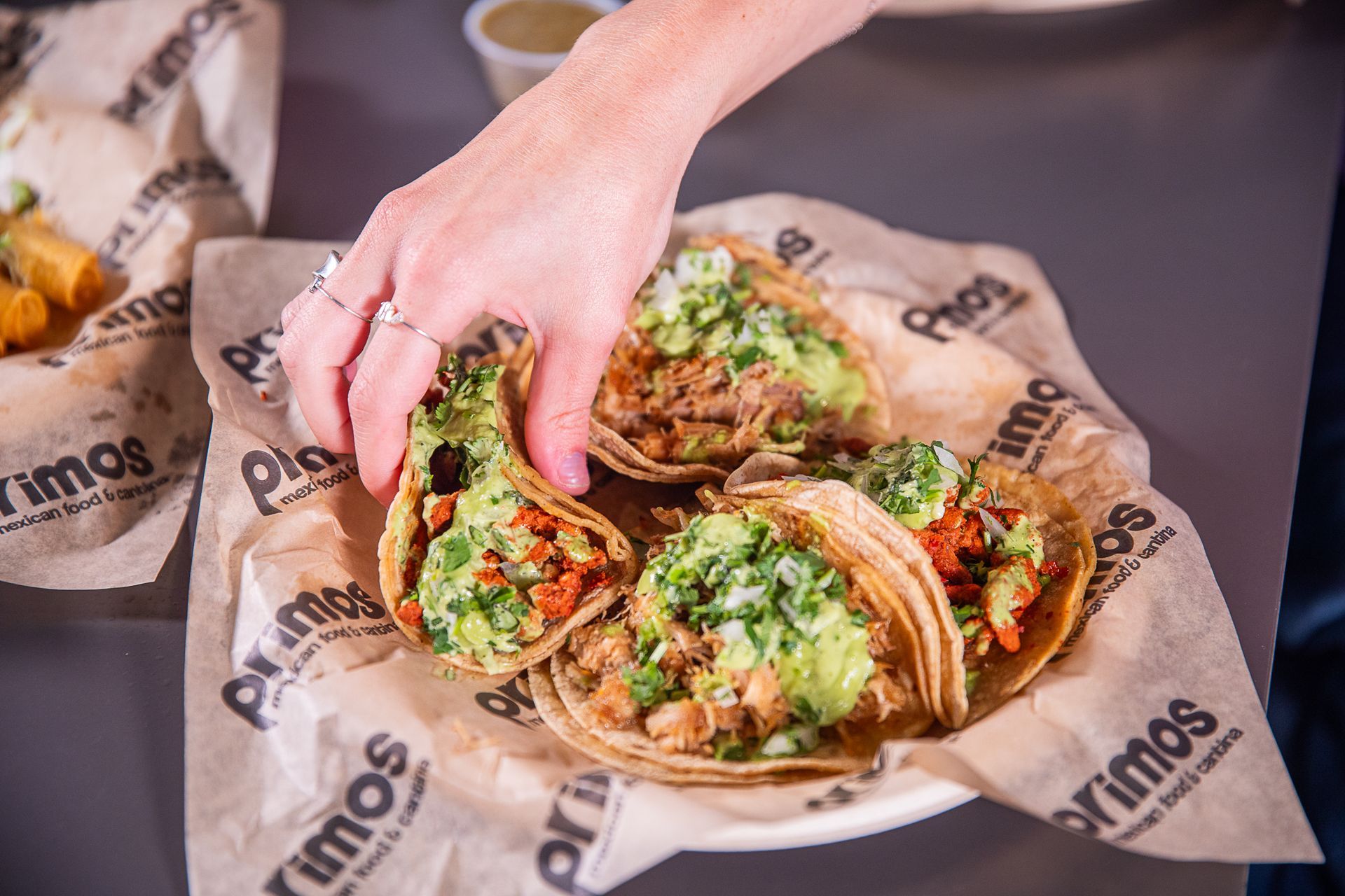 Hand reaching for a taco from a basket of tacos at Primos.