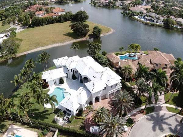 An aerial view of a large house surrounded by water and palm trees