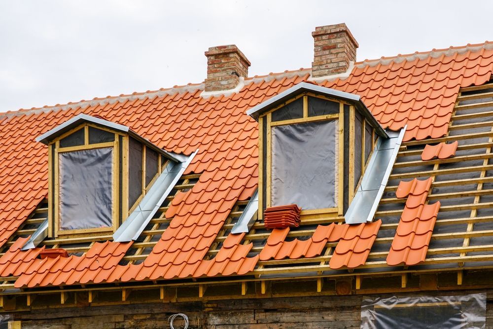 The roof of a house is being remodeled with red tiles.