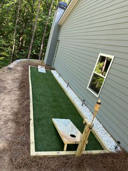 A bag toss game is being played in the backyard of a house.