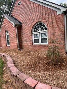 A brick house with arched windows and a brick wall in front of it.