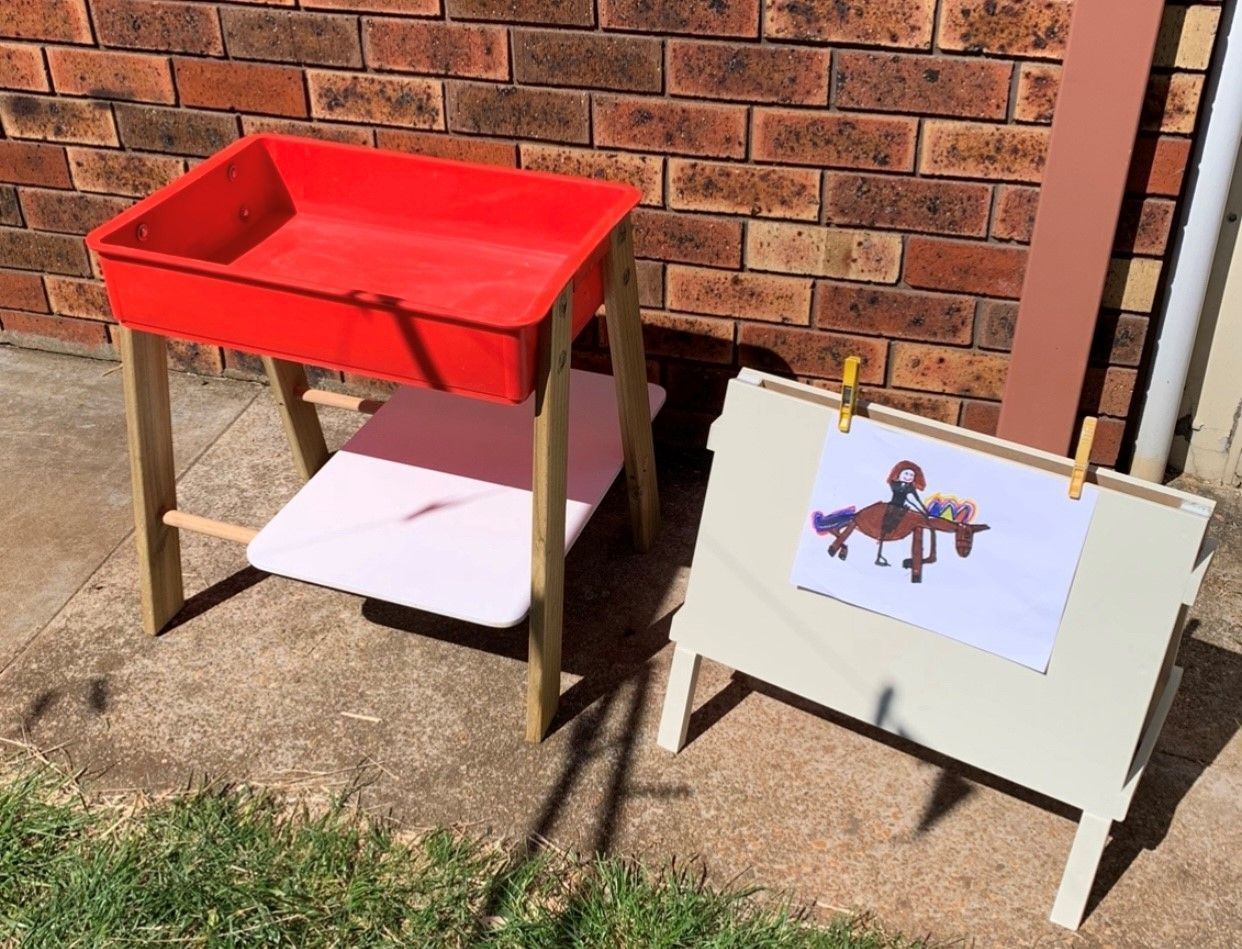 A wooden playground with a house and a sandbox in the middle of it.