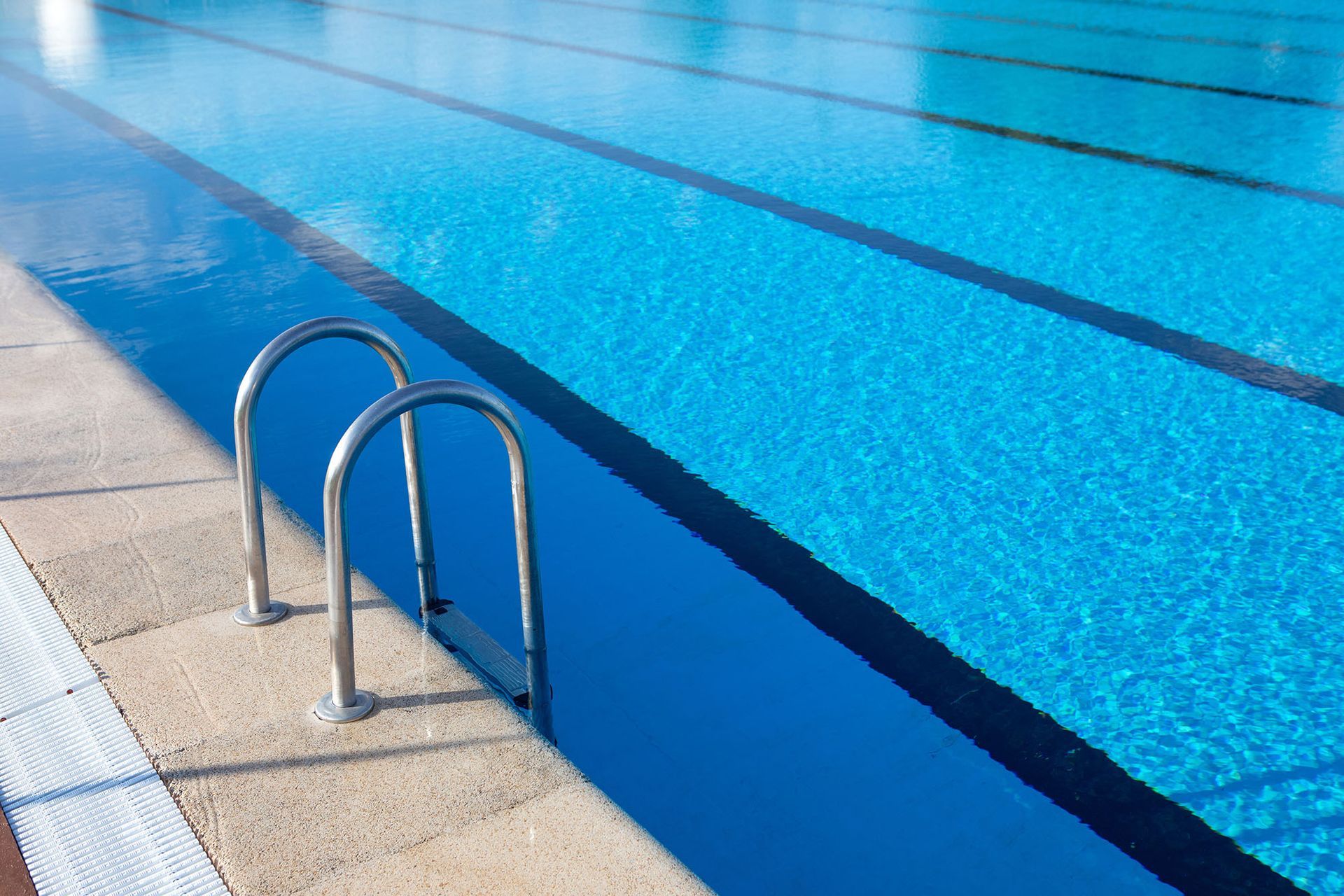 Pool with blue water and lane lines; metal ladder.