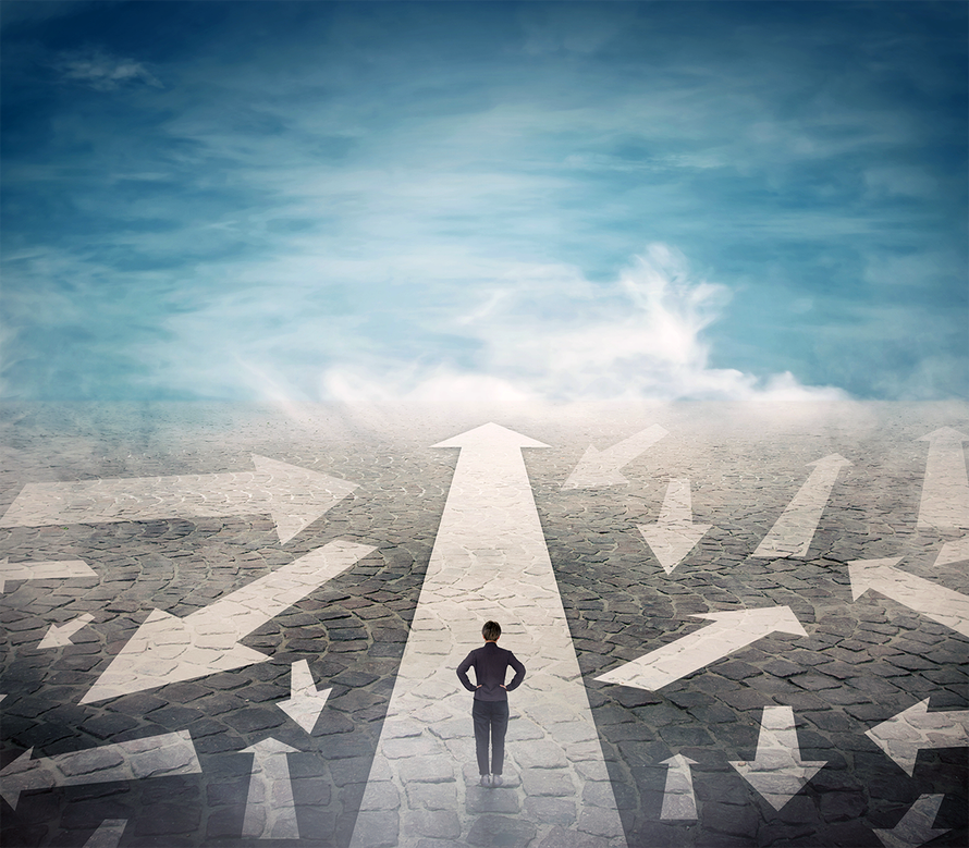 A man is standing in the middle of a road with arrows pointing in different directions.