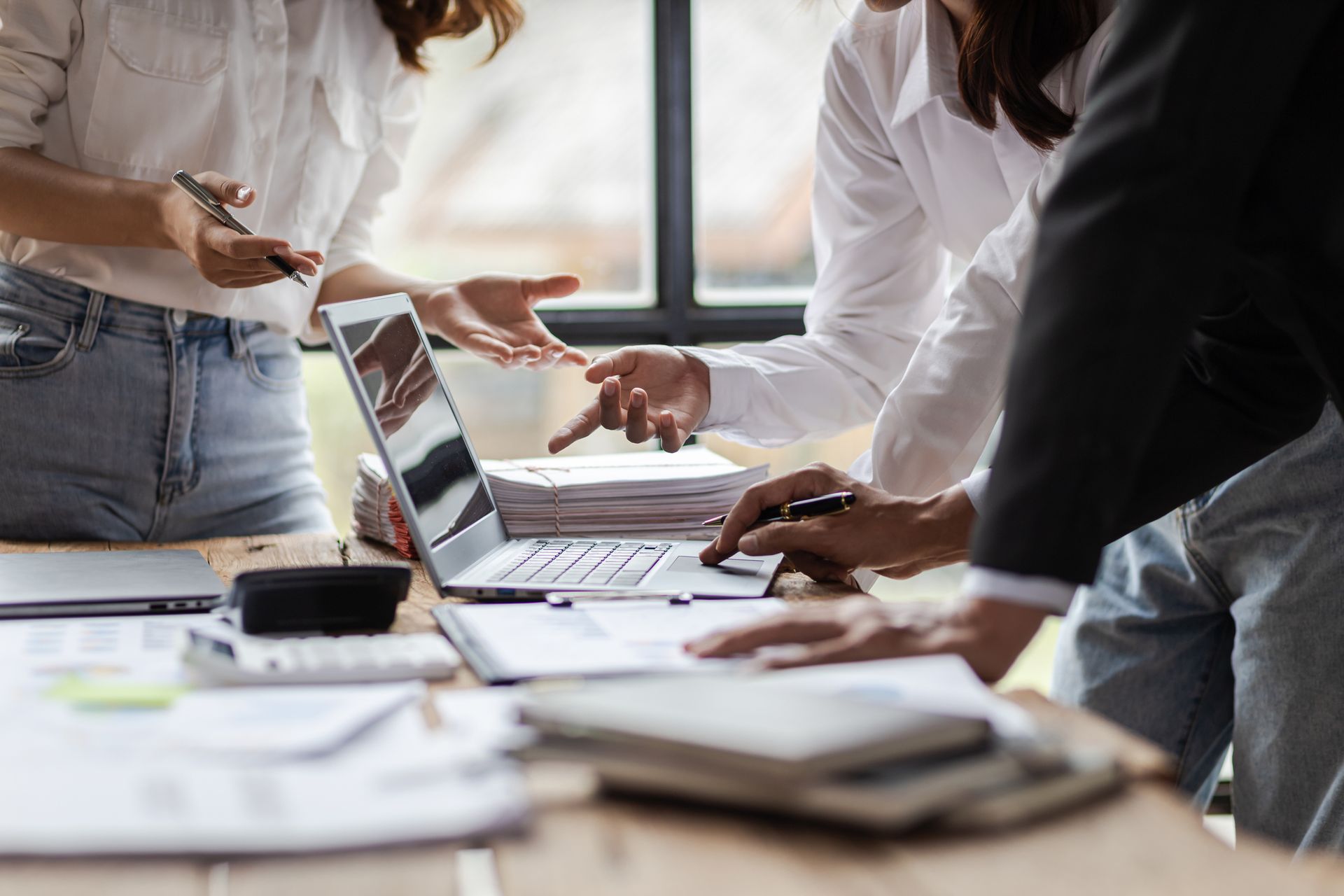 Persone che esaminano documenti e computer portatili attorno a un tavolo.