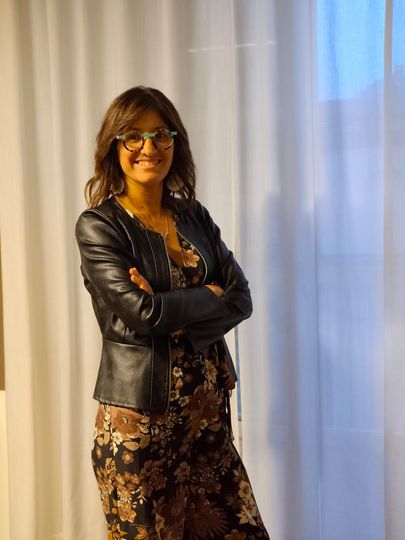 Due donne in un ufficio. Una lavora al computer portatile, l'altra legge un libro. Sullo sfondo, scaffali di libri.