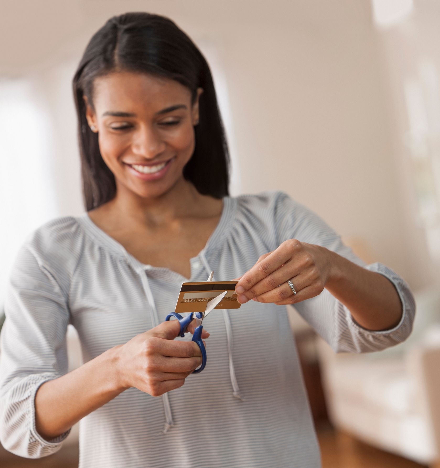 A woman is cutting a credit card with scissors