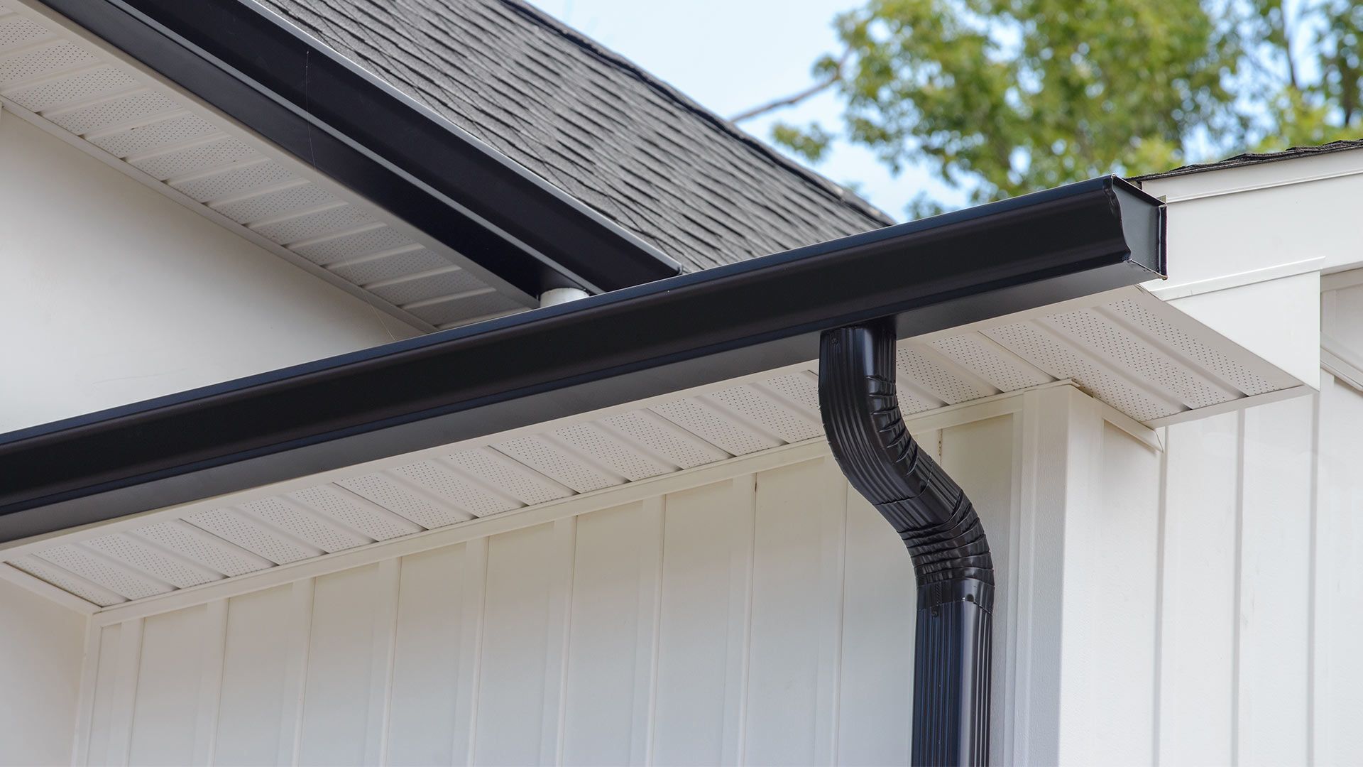 A close up of a black gutter on the side of a house.