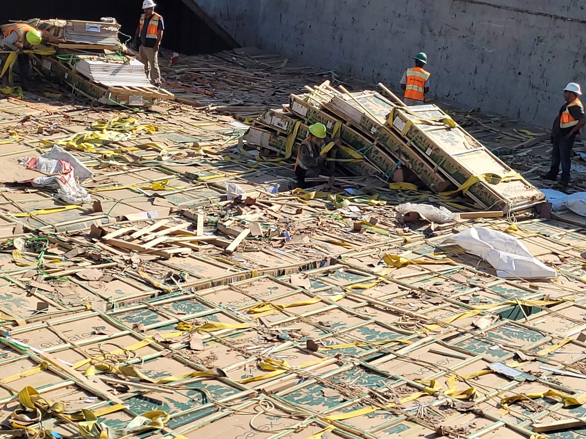 A group of construction workers are standing around a pile of cardboard boxes