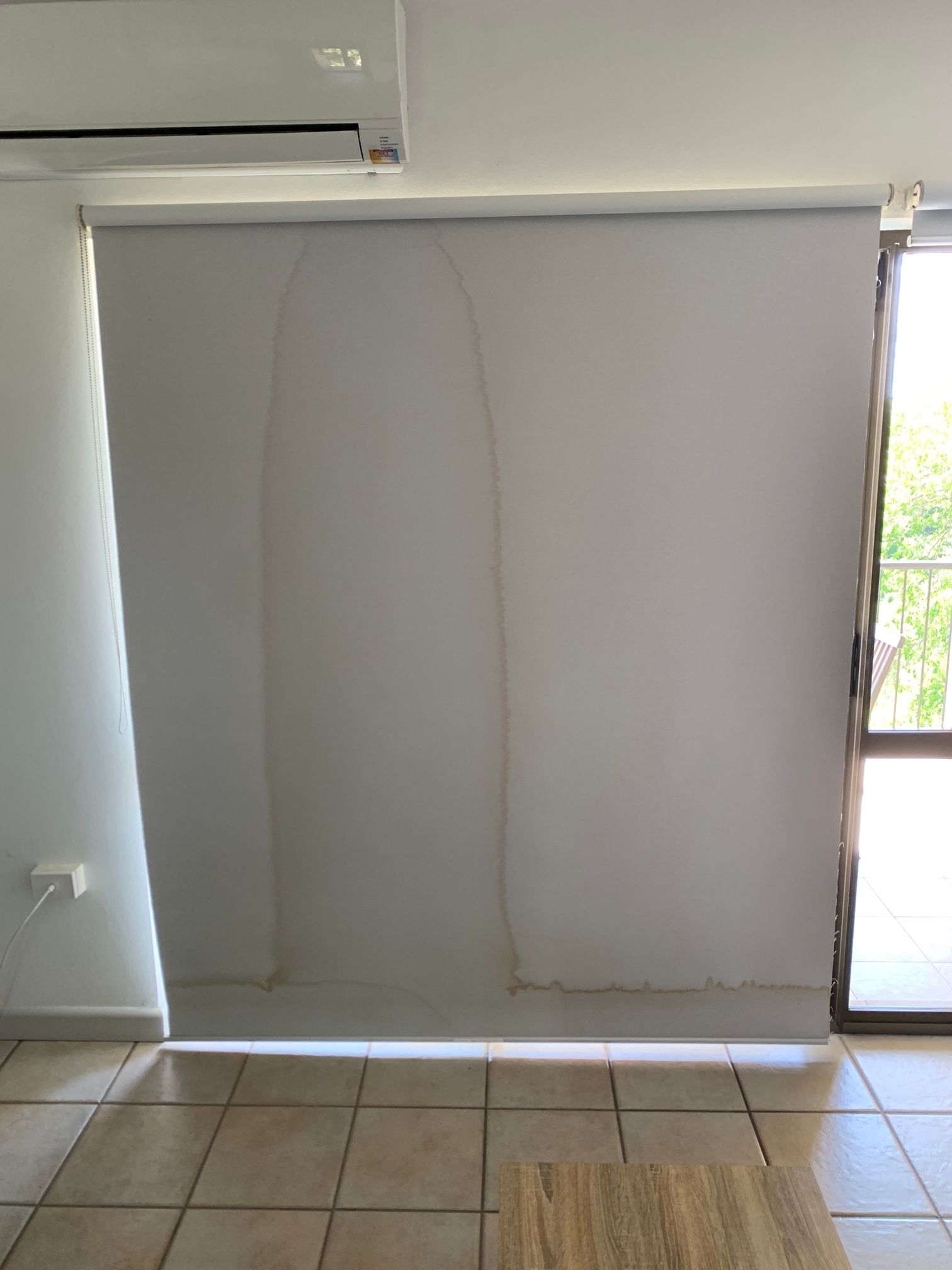 A white blind is hanging on a window in a living room.