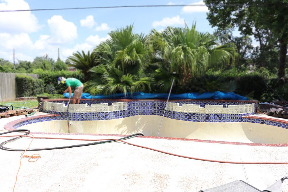 A man is working on a swimming pool in a backyard.