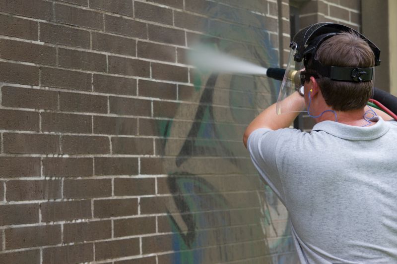 A man is cleaning a brick wall with a high pressure washer