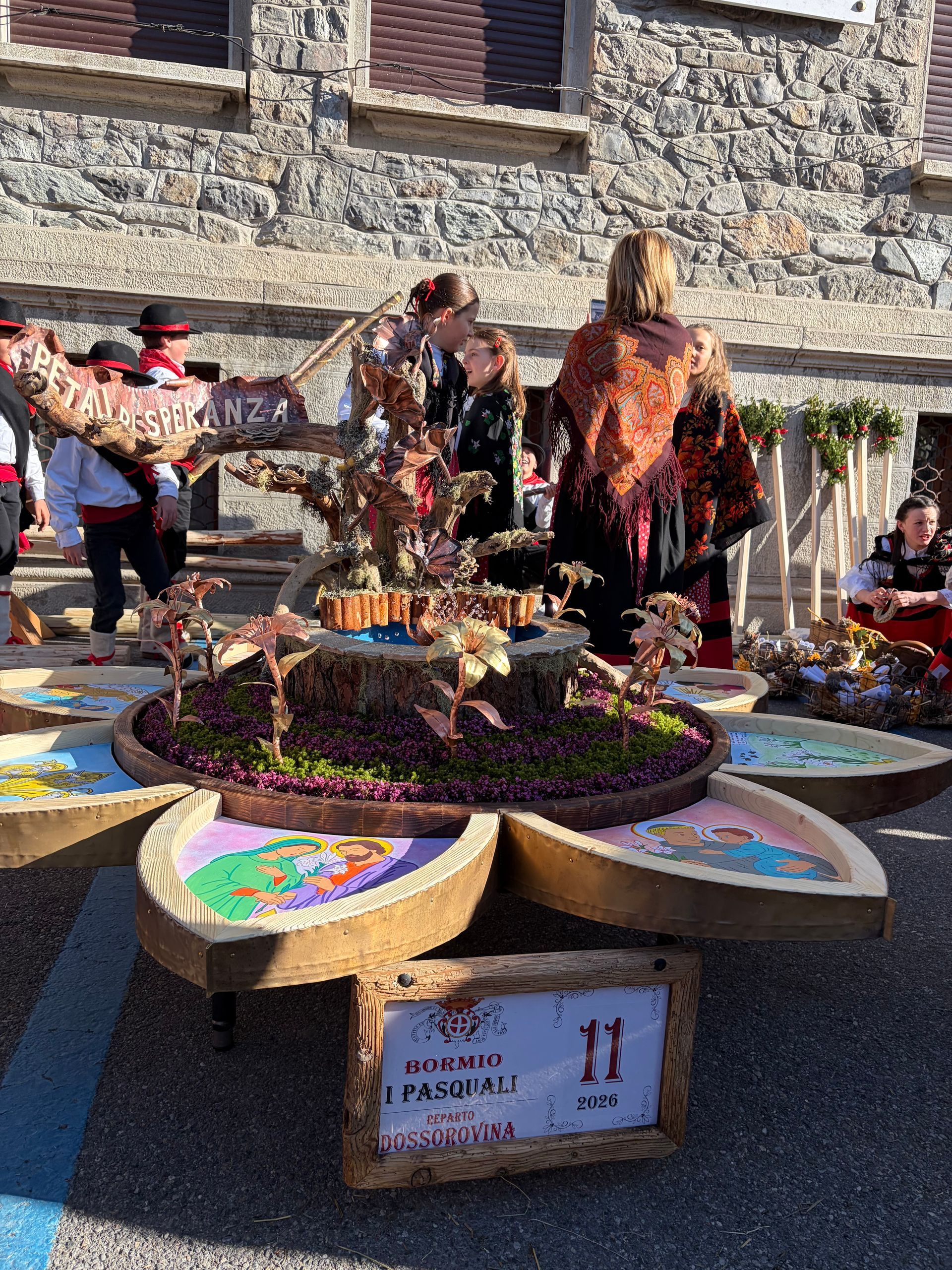 Un gruppo di persone è in piedi attorno a un carro fatto di fiori.