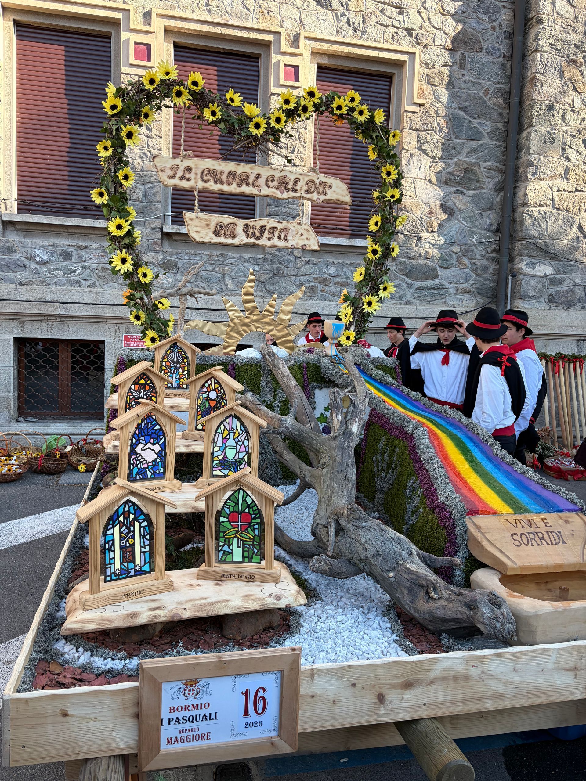Un carro di legno con un orologio è parcheggiato davanti a un edificio in pietra.