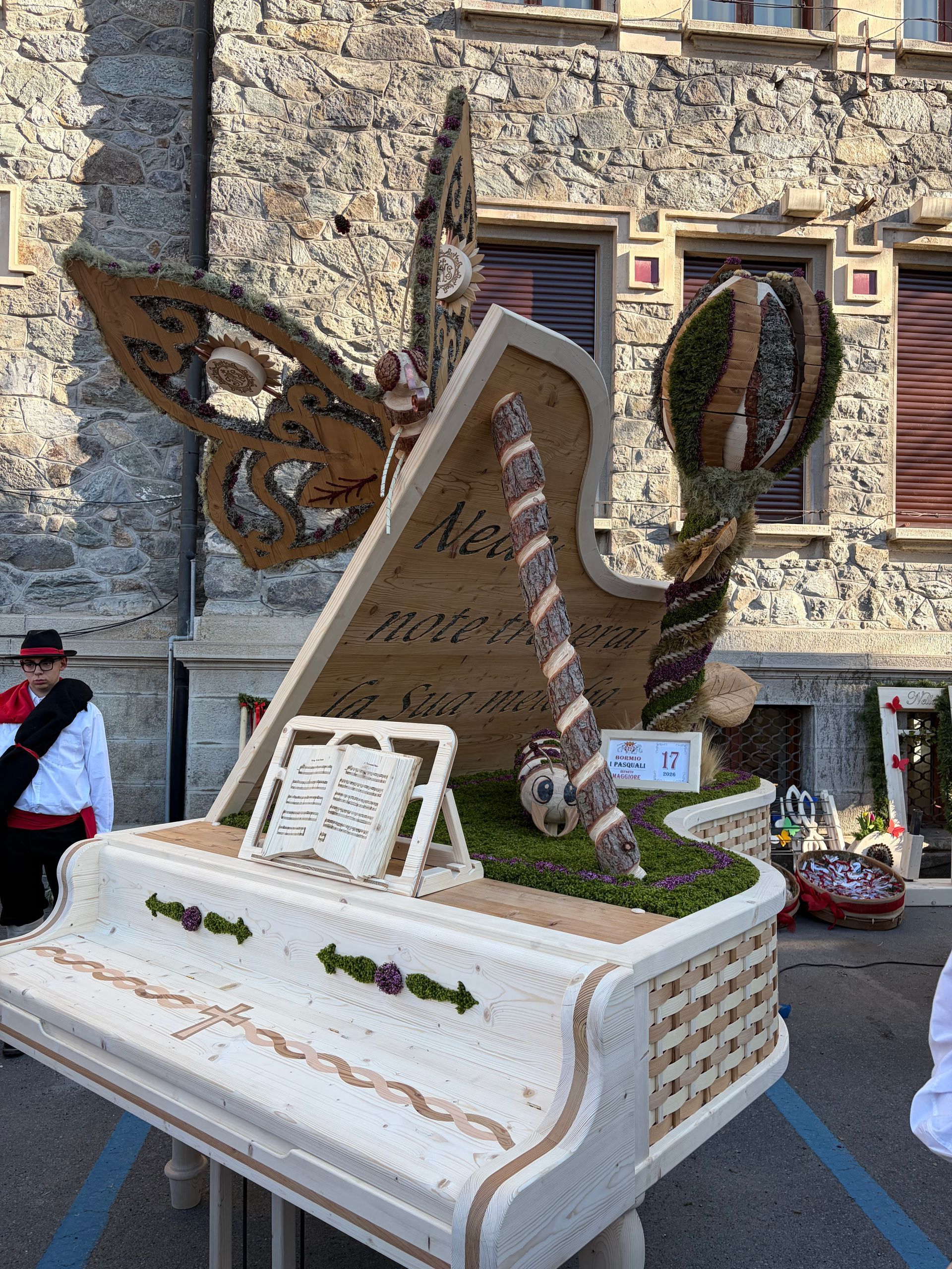 Una ruota panoramica fatta di legno e fiori è esposta durante una parata.