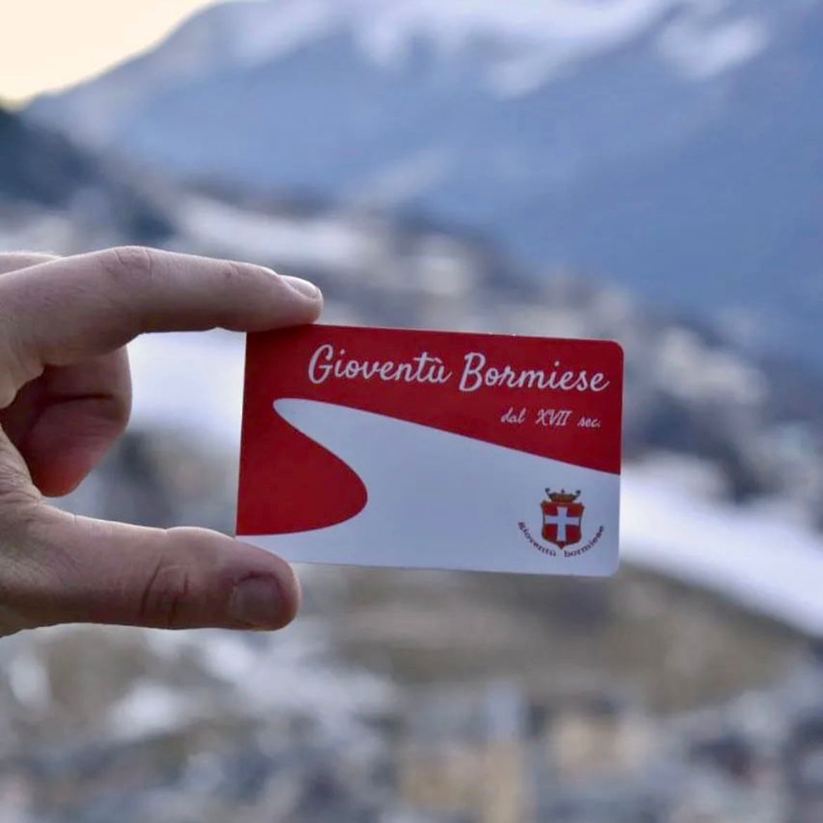 Una persona tiene in mano un cartellino rosso e bianco con la scritta giovanta bormise