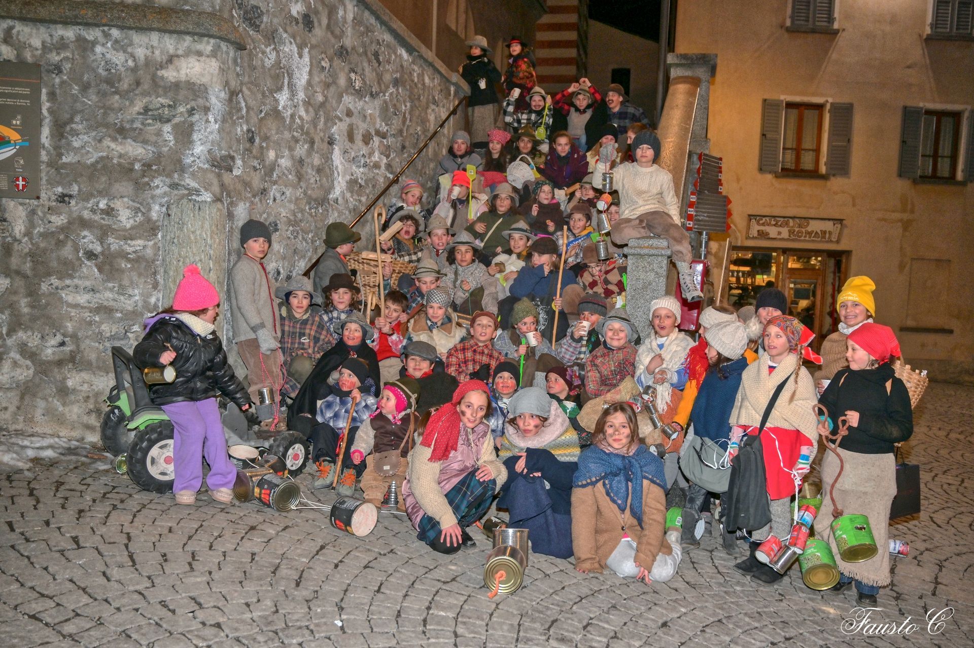 Un gruppo di bambini vestiti in costume posa per una foto su una strada acciottolata.