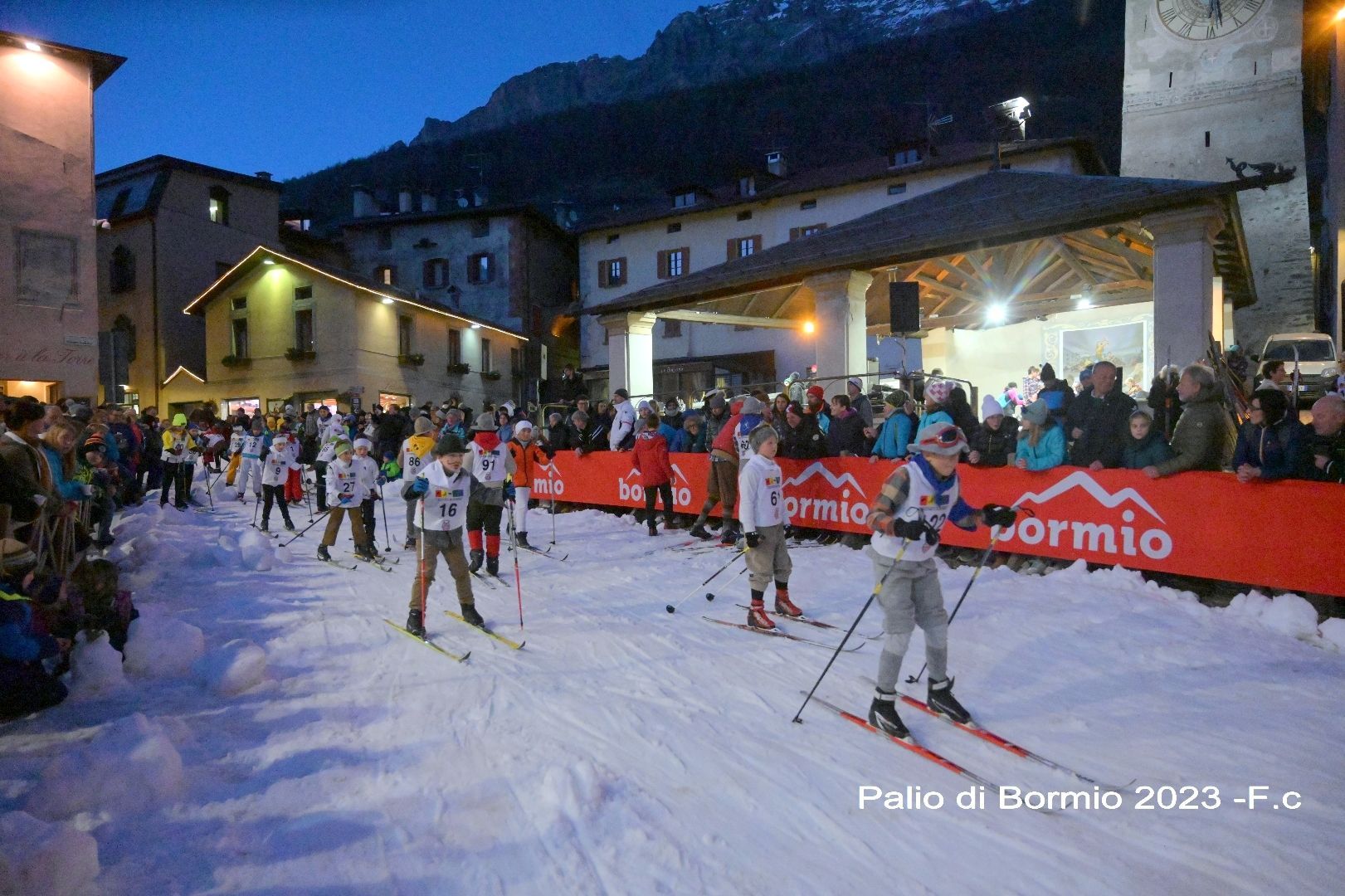 Un gruppo di persone scia sulla neve davanti a un edificio.