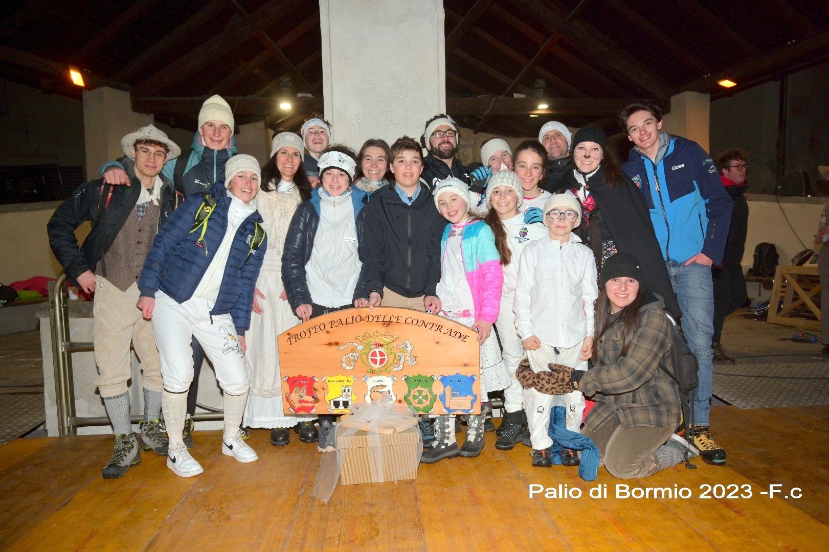Un gruppo di persone posa per una foto su un pavimento di legno.
