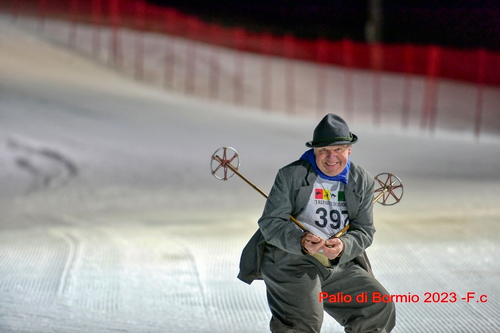 Un uomo in giacca e cappello sta sciando lungo un pendio coperto di neve.