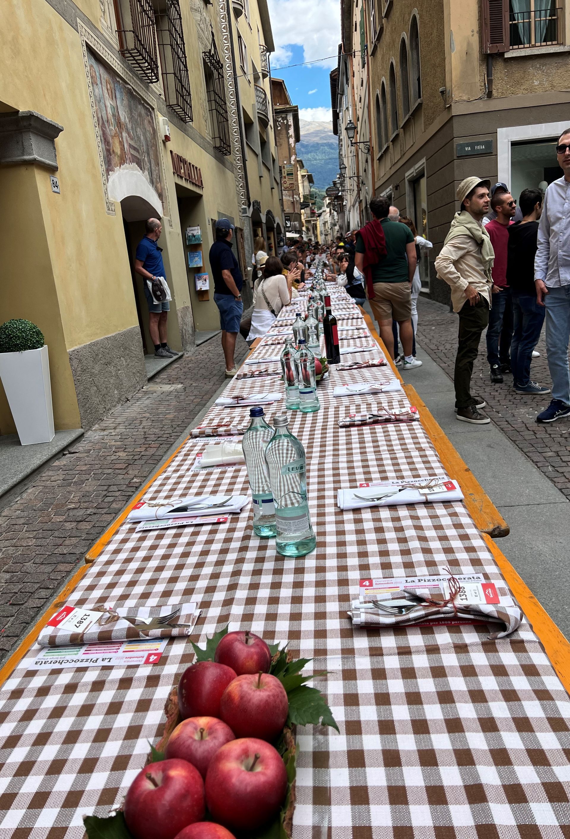 Un lungo tavolo con sopra delle mele è seduto sul lato di una strada.