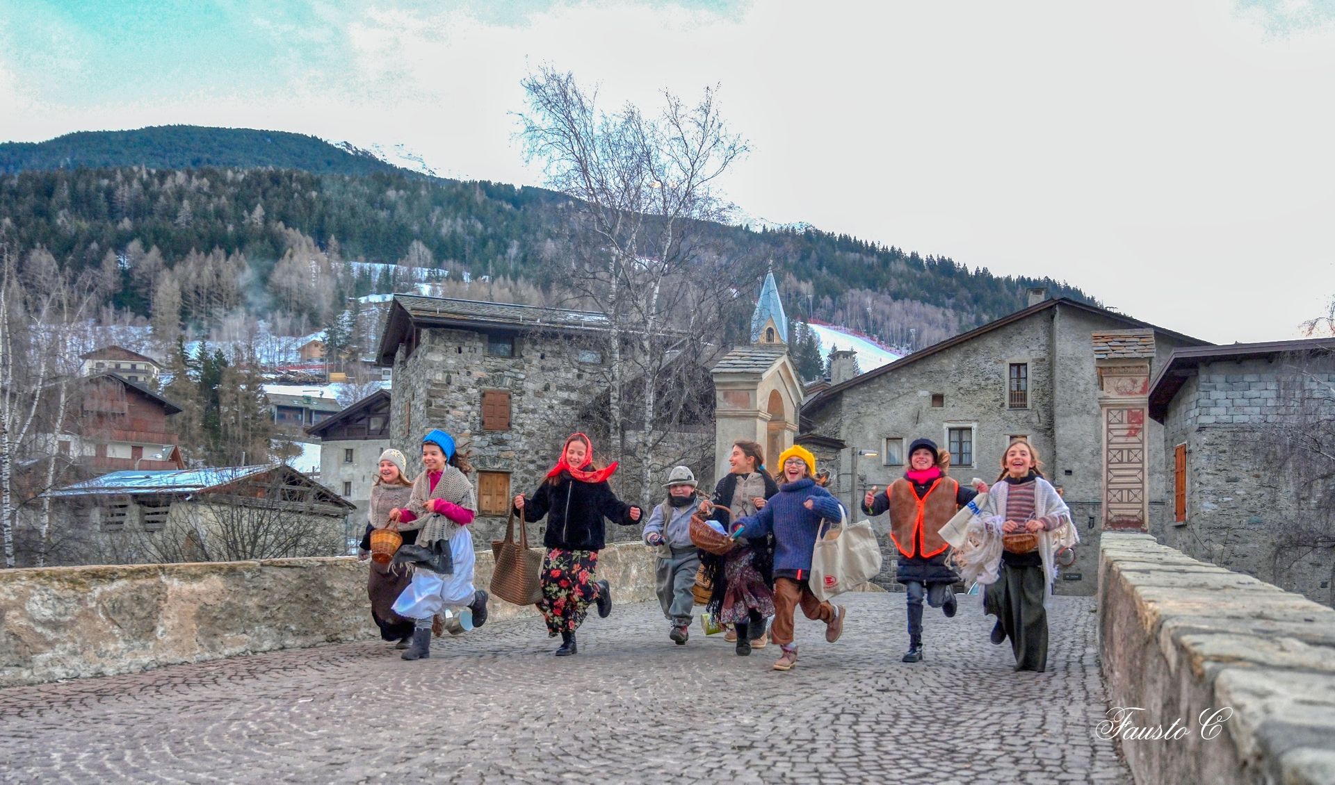 Un gruppo di bambini corre su una strada acciottolata.