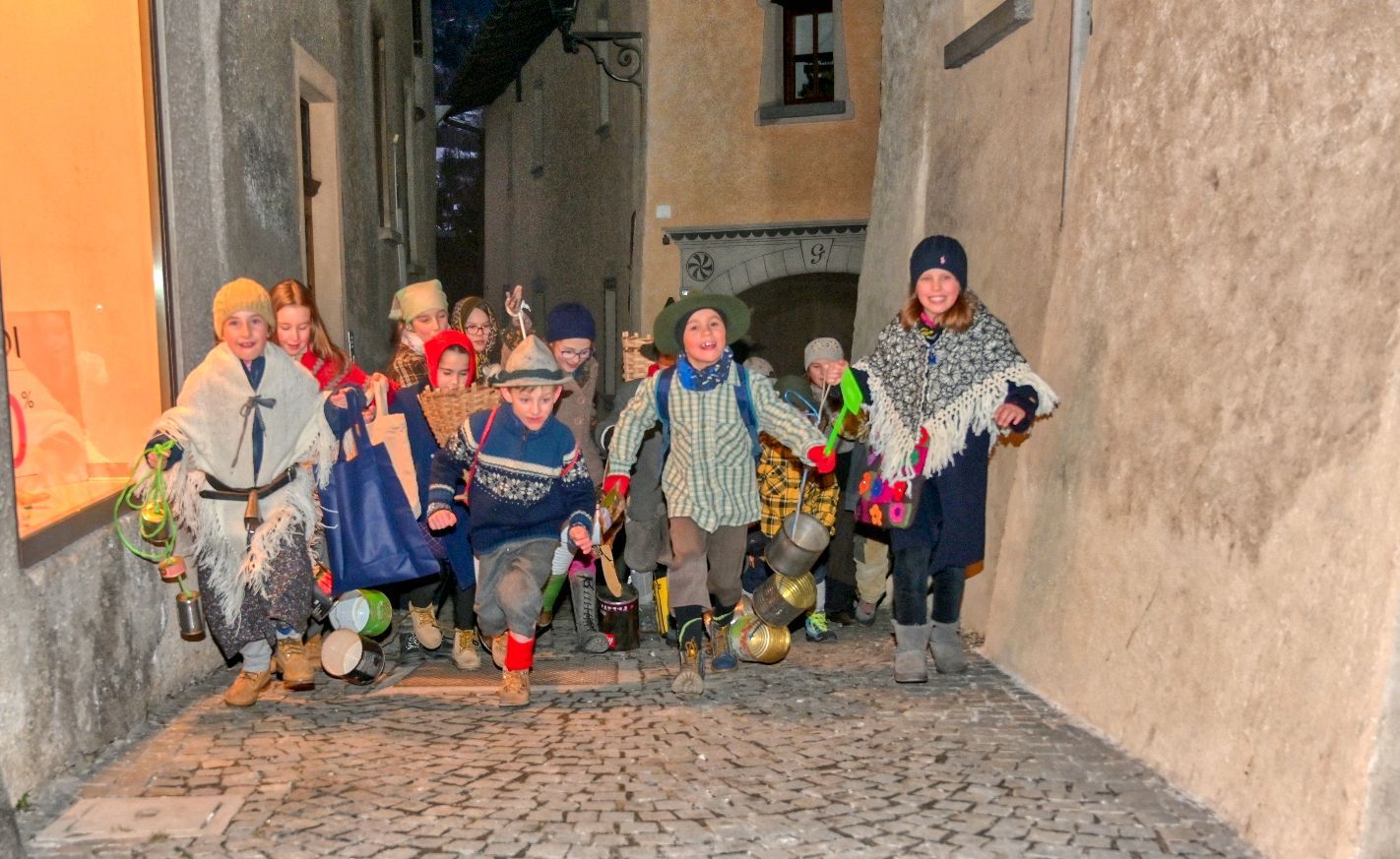 Un gruppo di bambini corre lungo una strada acciottolata.