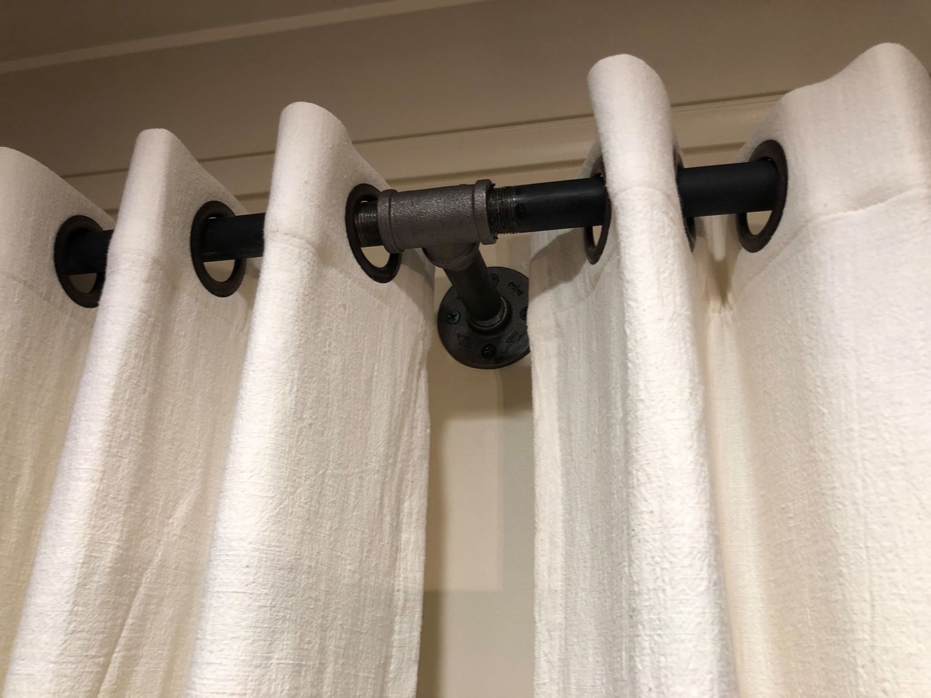 A close up of a pair of white curtains with grommets