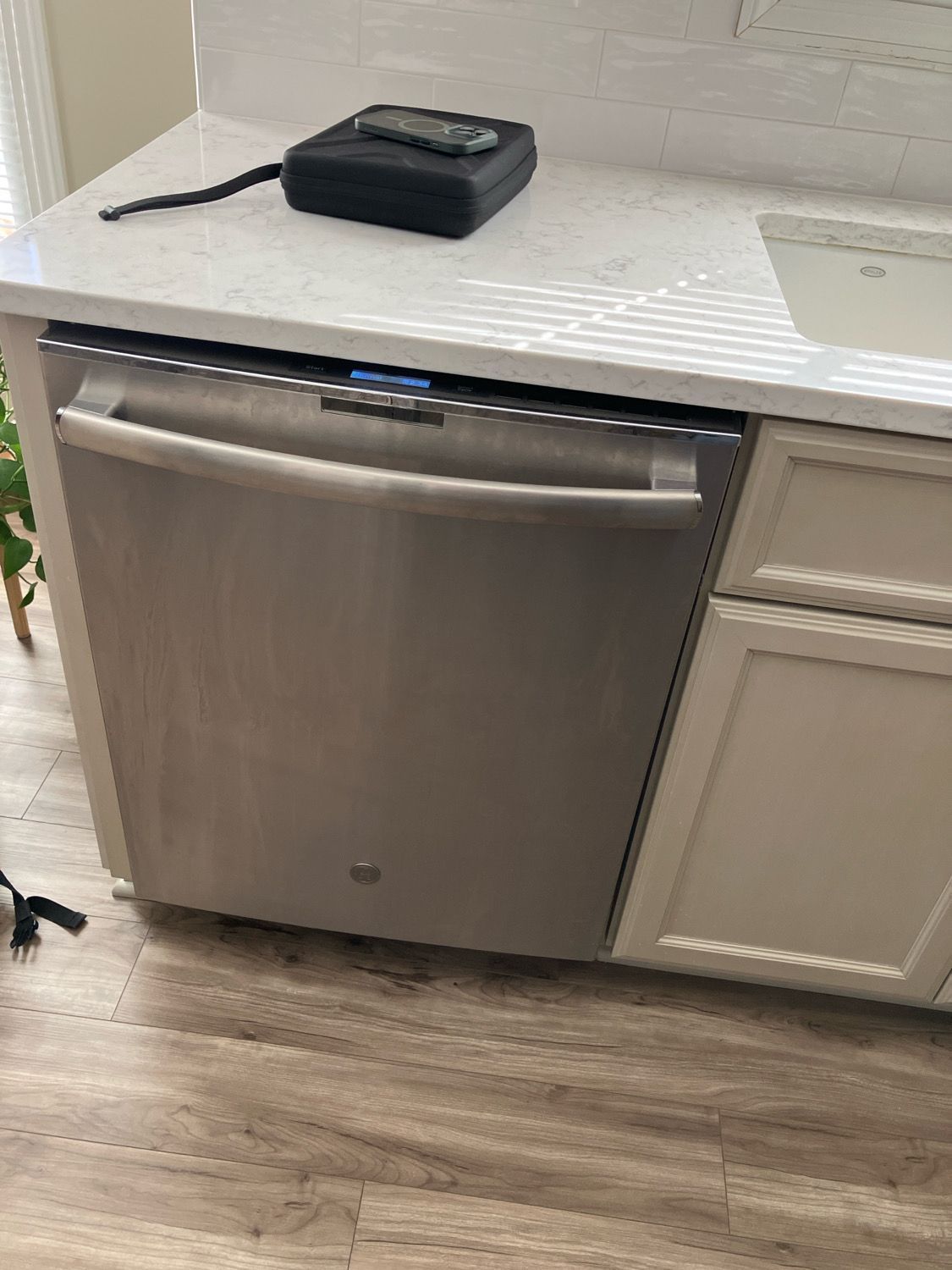 A stainless steel dishwasher is sitting on top of a counter in a kitchen.