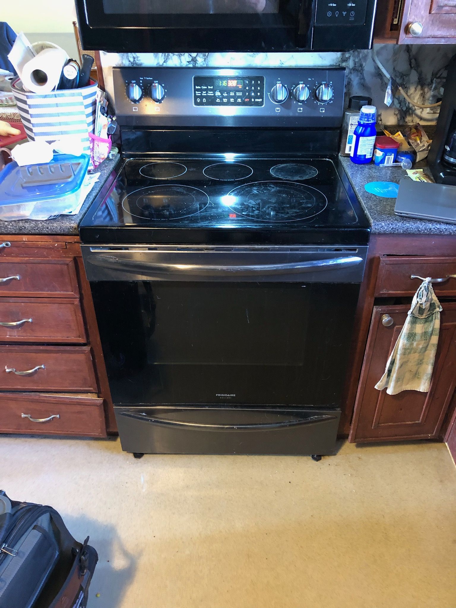 A black stove top oven is sitting in a kitchen next to a microwave.