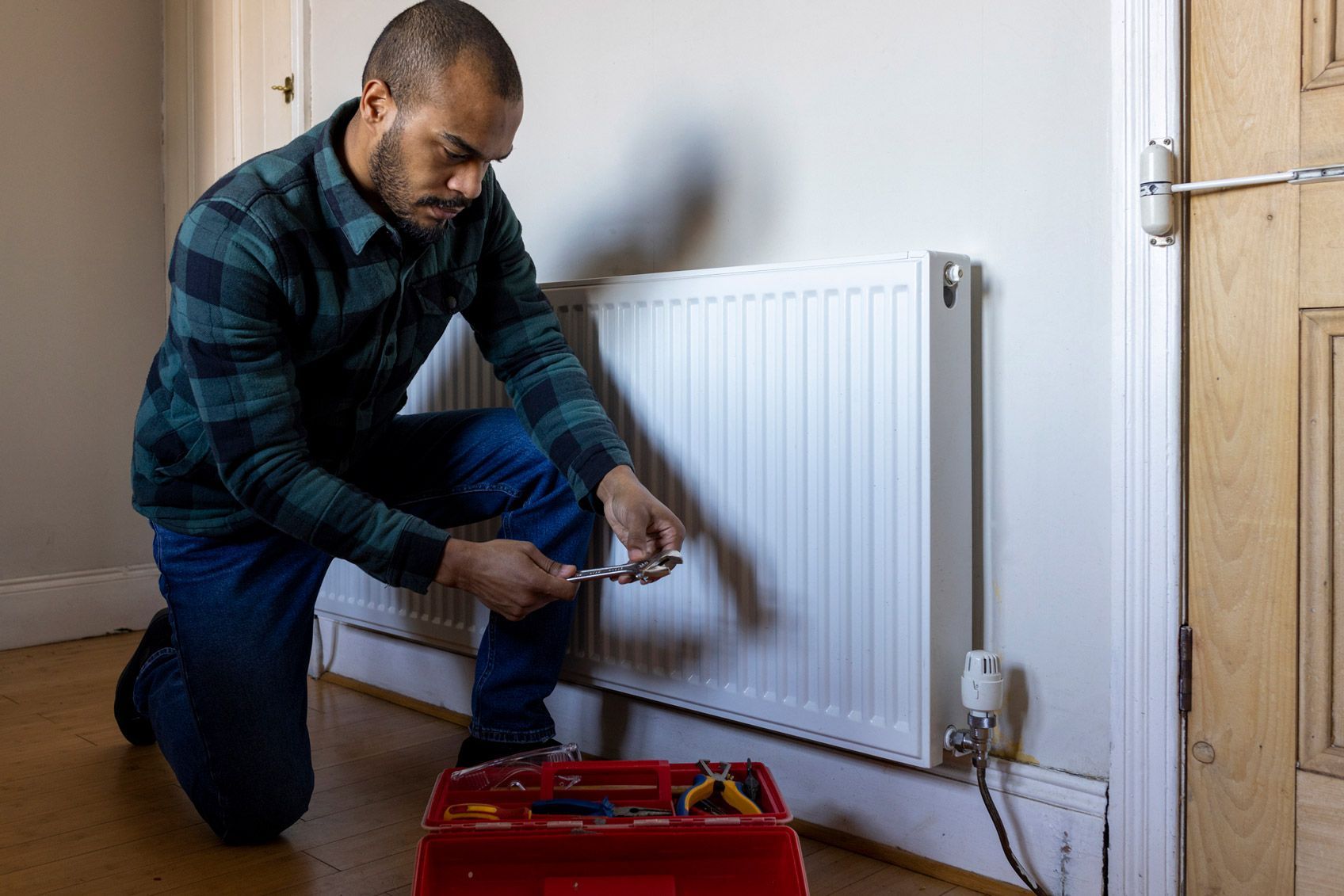 Man maintaining a radiator at a home in order to conserve energy. Man maintaining a radiator at a home in order to conserve energy.