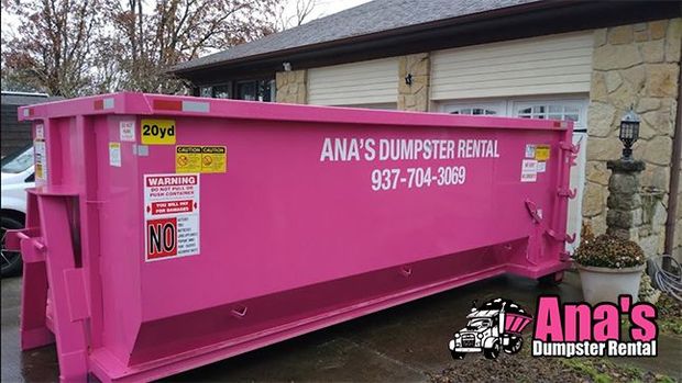Pink Ana’s Dumpster Rental dumpster parked outdoors beside a house