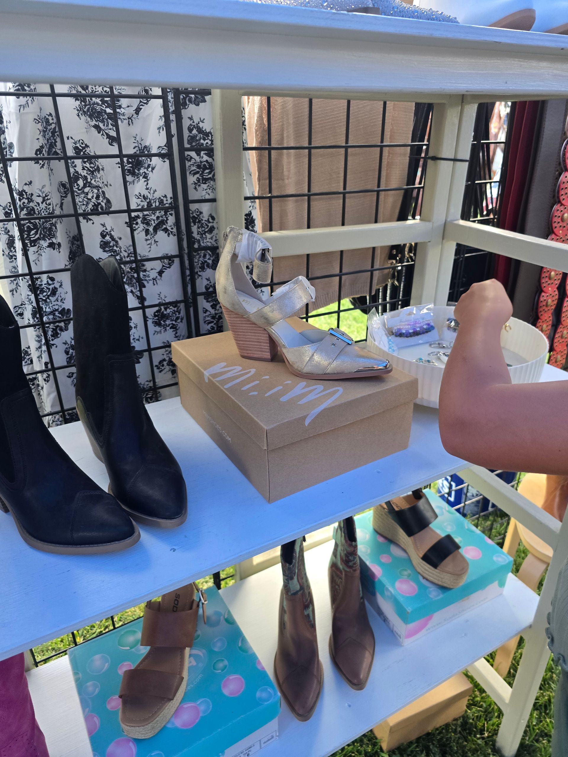 Shoes displayed on a multi-tiered shelf at an outdoor market.