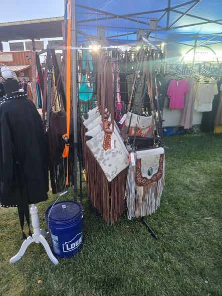 Booth with leather bags, clothing, and a mannequin at an outdoor market.